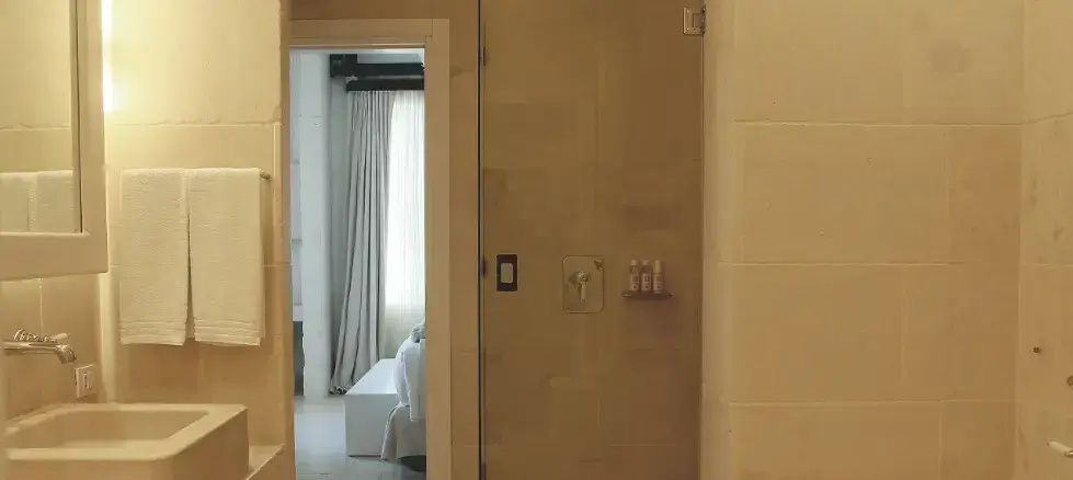 Moderne Glasdusche im Badezimmer mit Blick auf den angrenzenden Schlafbereich.