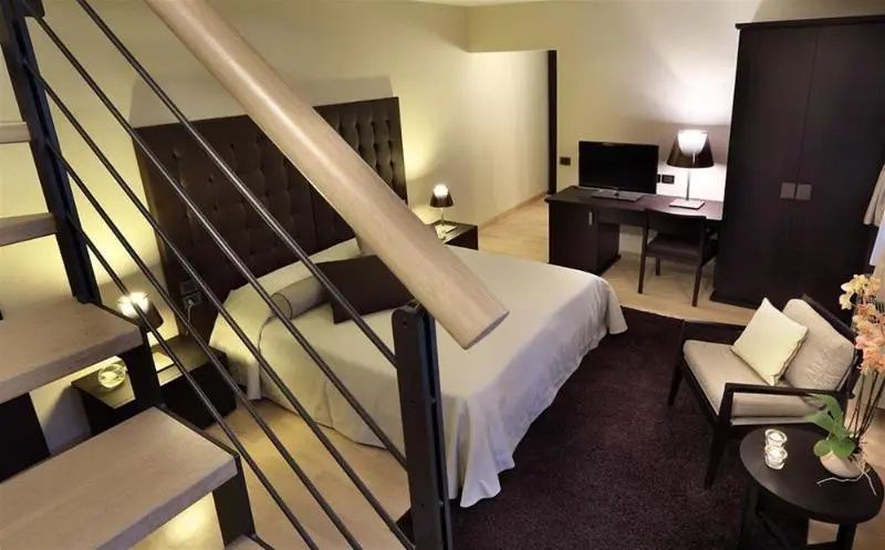 Modernes Hotelzimmer mit einem Doppelbett, einem Schreibtisch und einer Treppe.