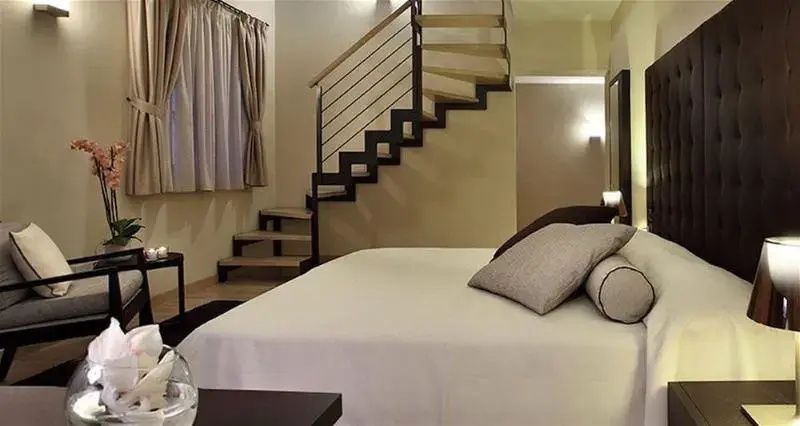 Helles Schlafzimmer mit Treppe zur Galerie und frisch bezogenem Doppelbett.