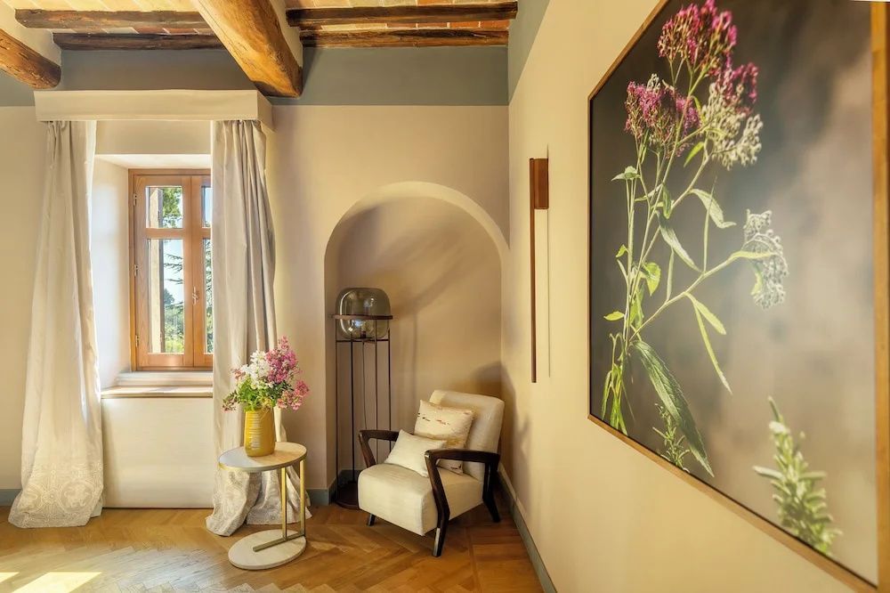 Sessel in einer Wandnische im Hotelzimmer neben einem Beistelltisch mit frischen Blumen.