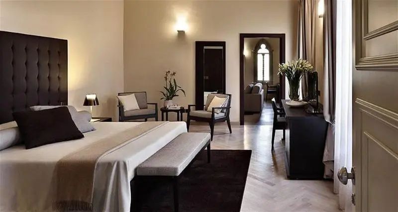 Geräumige Suite mit Doppelbett, Sitzbereich und Blick in ein weiteres Zimmer.