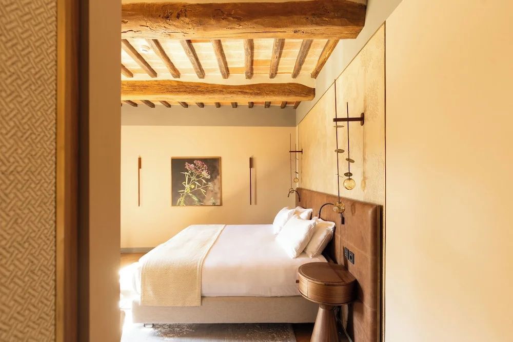 Hotelzimmer mit Holzbalkendecke, Doppelbett und braunem Kopfteil.