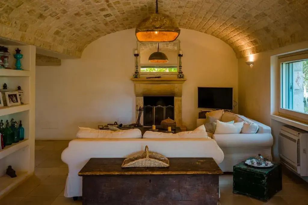 Wohnbereich unter einer Steinwölbung mit Kamin und hellem Sofa.