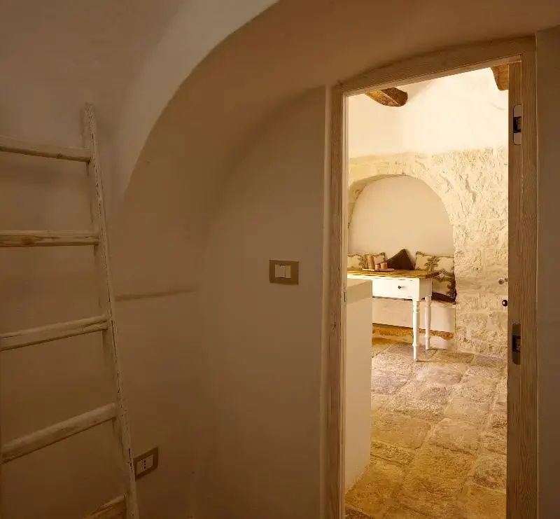 Blick durch eine geöffnete Tür auf ein Zimmer mit hellem Natursteinbogen und Holztisch.