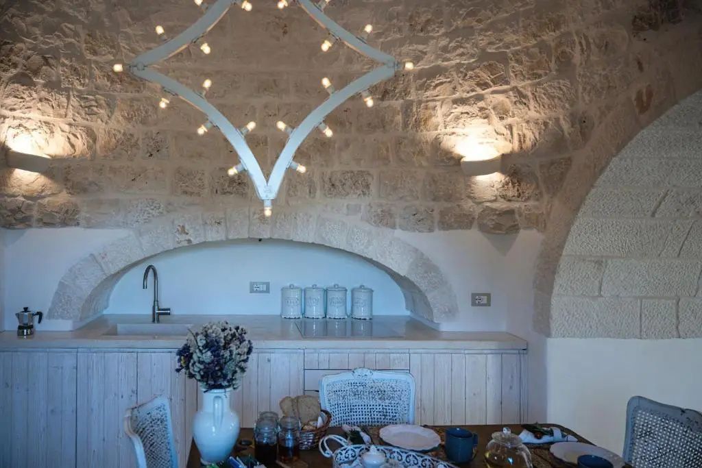 Essbereich unter einer Gewölbedecke aus Naturstein mit gedecktem Tisch und ausgefallener Lampe.
