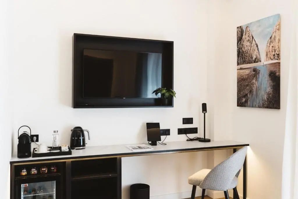 Schreibtischbereich im Zimmer mit wandmontiertem Fernseher und Schreibtischstuhl.