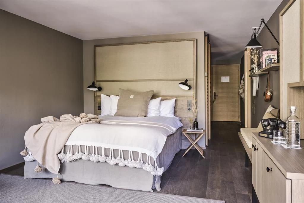 Doppelbett mit hellem Kopfteil und Kissen in einem modern eingerichteten Hotelzimmer.