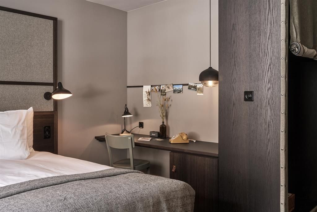 Schreibtisch aus Holz mit Stuhl, Wanddeko und Telefon im Hotelzimmer.