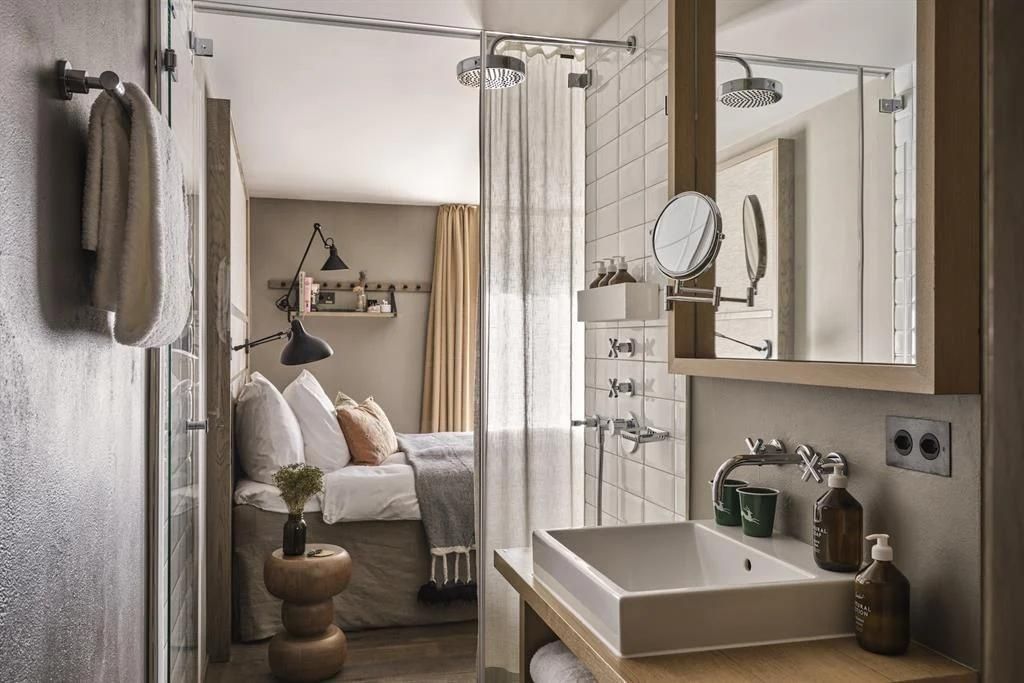 Badezimmer mit rechteckigem Waschbecken, Dusche und Blick in den Schlafbereich.