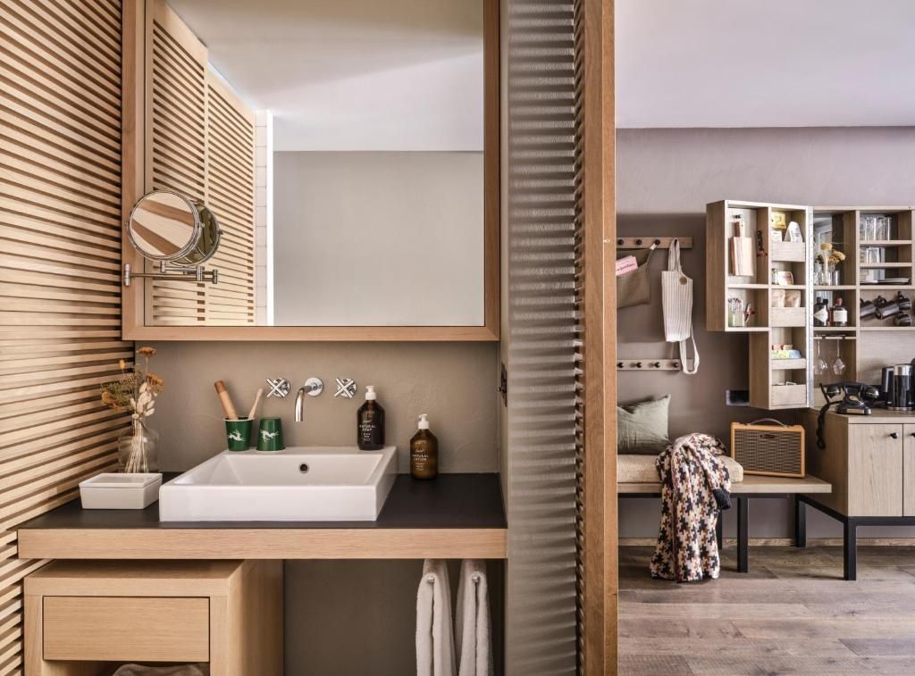 Waschtisch im Badezimmer mit Holzrahmenspiegel und Blick auf die angrenzende Garderobe.