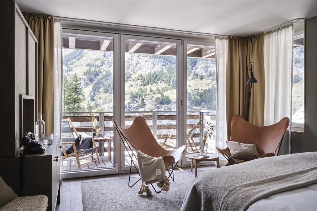 Blick aus dem Schlafzimmer durch große Fensterscheiben auf den Balkon und die Berge.