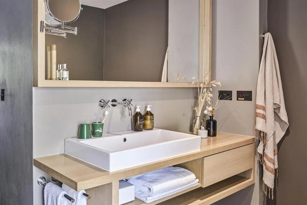 Modernes Badezimmer mit einem weißem Waschbecken auf einer Konsole aus hellem Holz.