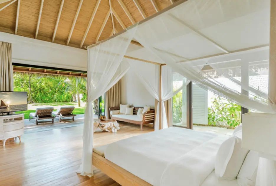 Helles Schlafzimmer mit Himmelbett, weißem Moskitonetz und Blick zur Terrasse.