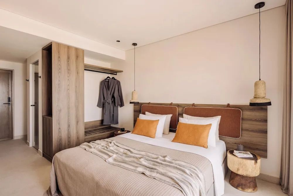 Doppelbett mit braunen Kissen und offener Kleiderschrank mit Bademänteln.