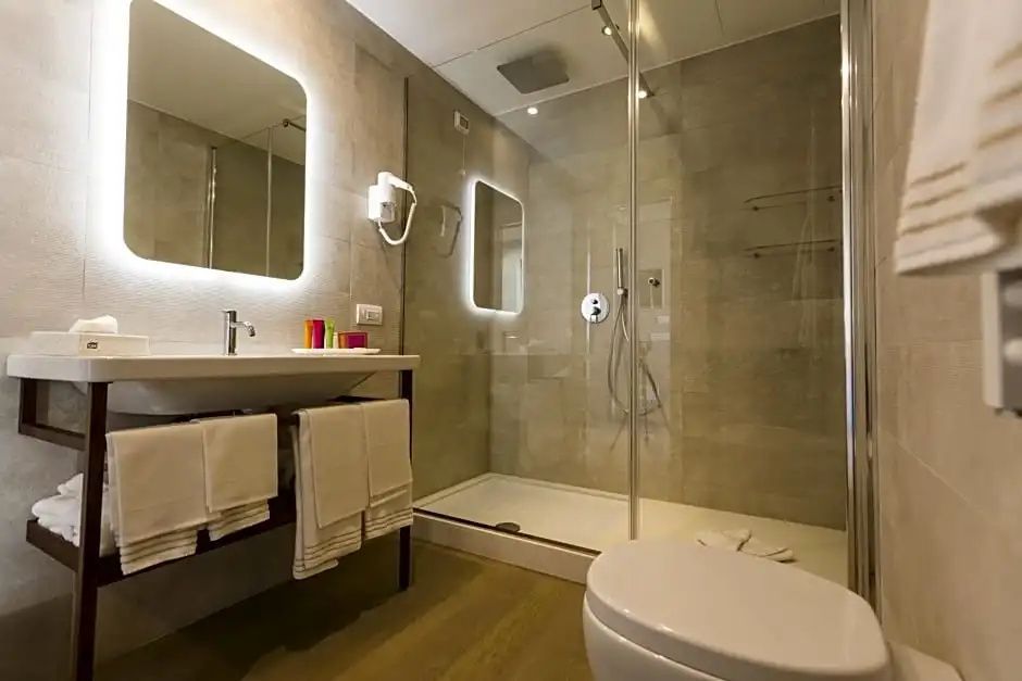 Modernes Badezimmer mit beleuchtetem Spiegel, Waschtisch und Dusche hinter Glas.