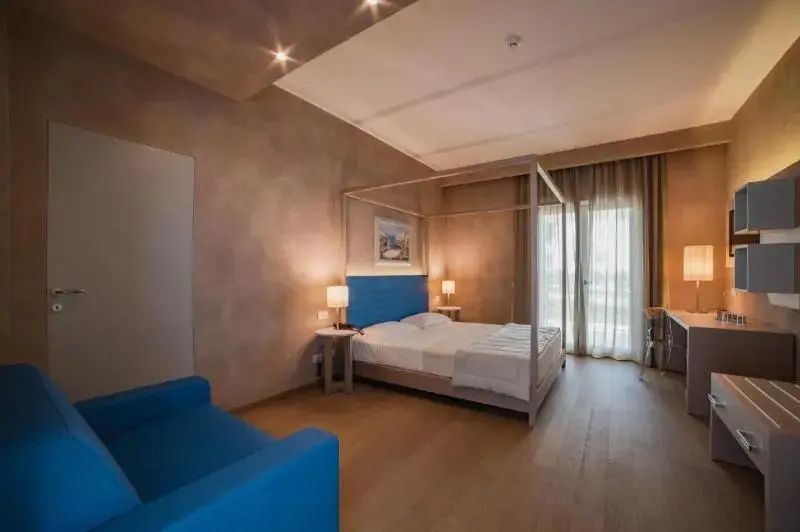 Zimmer mit einem Himmelbett aus Holz, blauem Kopfteil und blauem Sofa.
