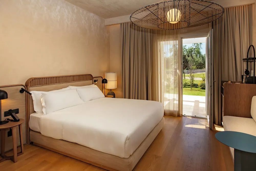 Helles Zimmer mit Doppelbett, Parkettboden und Blick in den Garten.