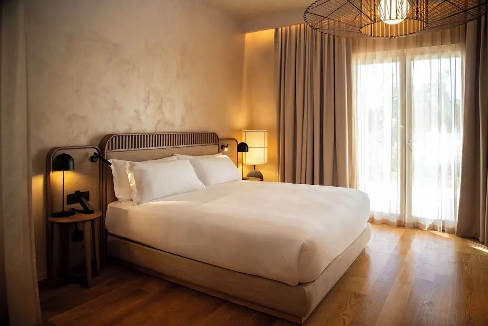 Doppelbett mit beigen Kissen und Kopfteil aus Holz im Hotelzimmer.