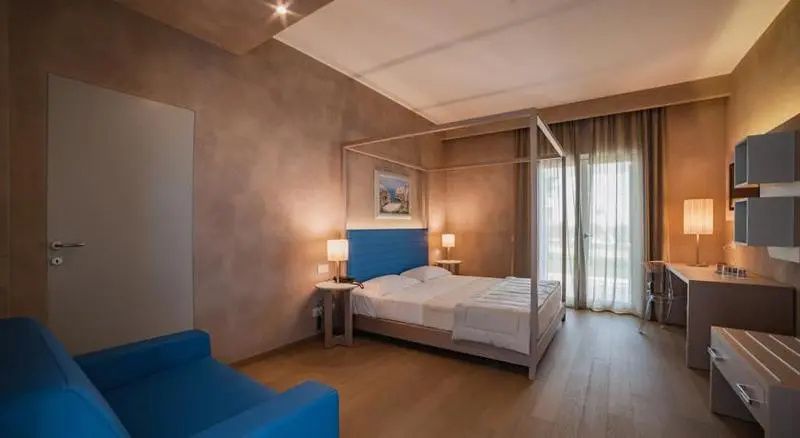 Hotelzimmer mit Himmelbett aus hellem Holz, blauem Kopfteil und Parkettboden.