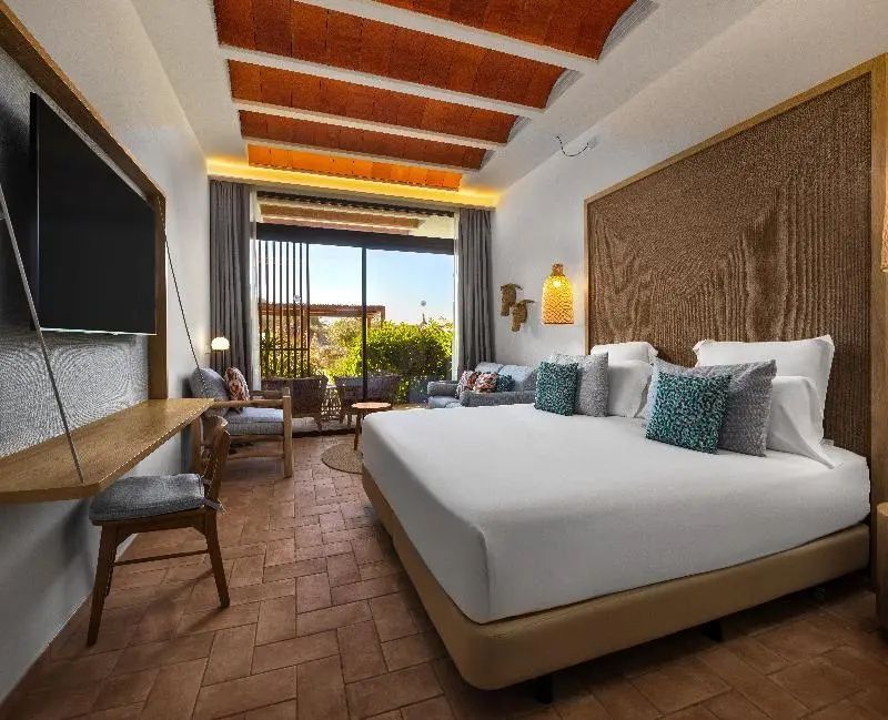 Geräumiges Hotelzimmer mit Fliesenboden, großem Doppelbett und Terrasse ins Grüne.