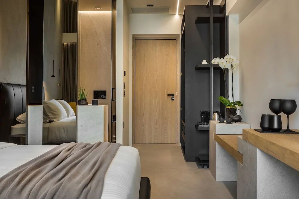 Eingangsbereich eines Hotelzimmers mit Holztür, Garderobe und weißer Orchidee.