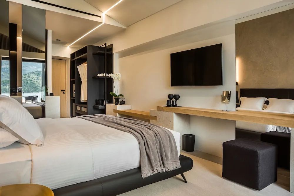 Modern eingerichtetes Hotelzimmer mit großem Doppelbett, Schreibtisch und Wandfernseher.