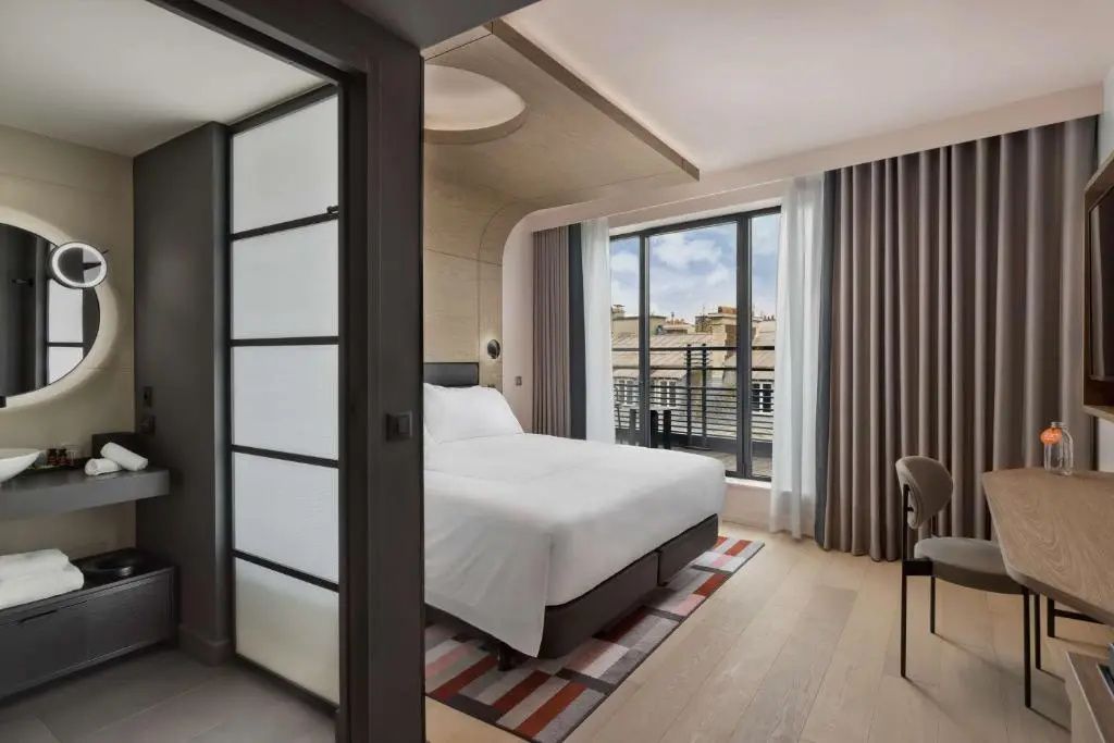 Modern eingerichtetes Hotelzimmer mit Doppelbett, Fensteraussicht und Parkettboden.