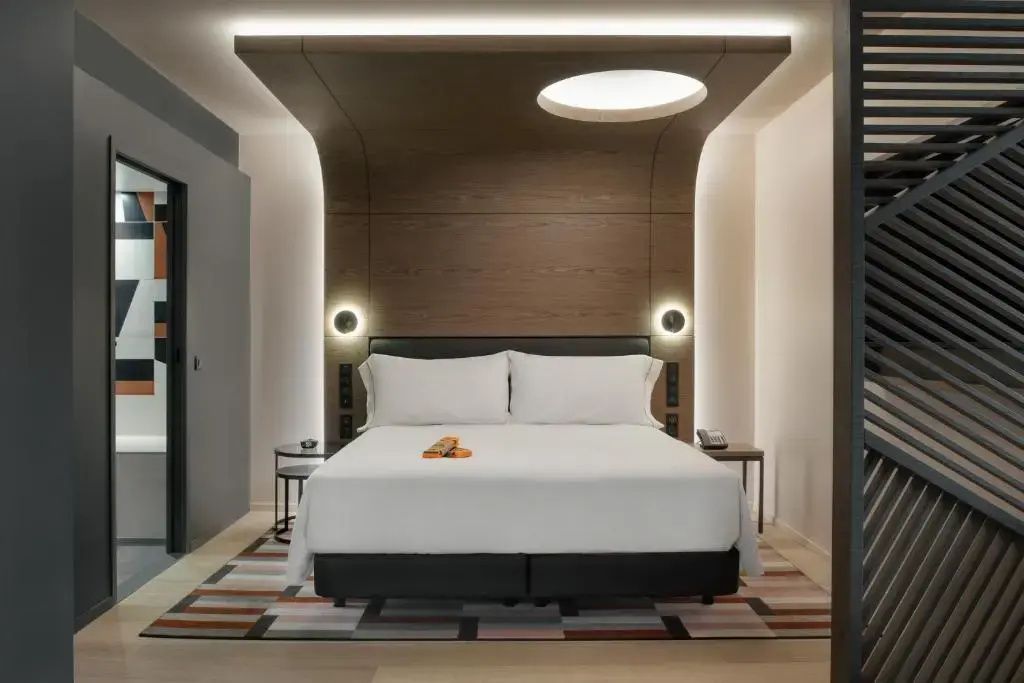 Doppelbett mit Holzpaneel an Wand und Decke sowie indirekter Beleuchtung im Zimmer.