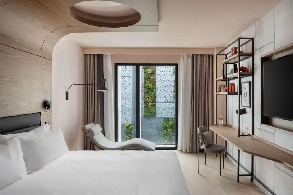 Hotelzimmer mit gemütlicher Liege, Schreibtisch und Blick auf eine bepflanzte Wand.