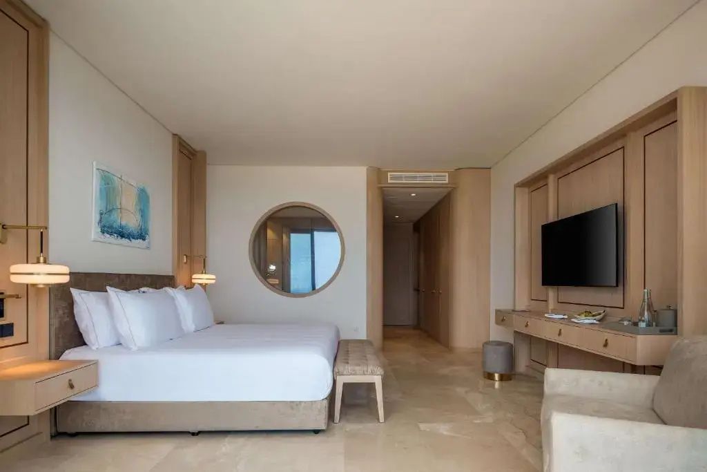 Helles Schlafzimmer mit Doppelbett, hölzerner Schrankwand und kreisförmigem Fenster.