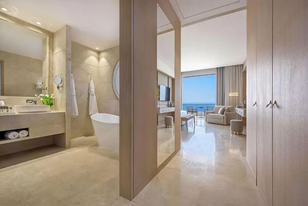 Offene Suite mit freistehender Badewanne auf der linken Seite und Wohnbereich mit Balkon.