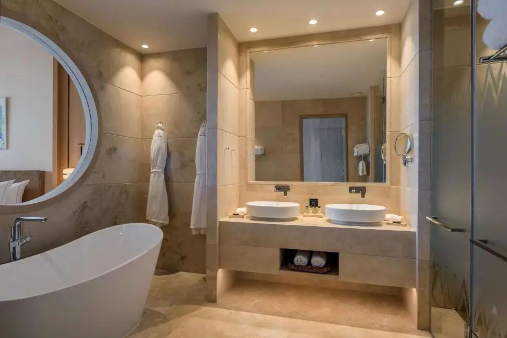 Badezimmer mit zwei Waschbecken, großem Wandspiegel und einer weißen Badewanne.