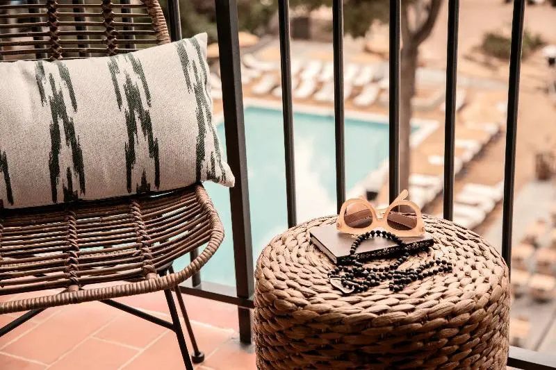 Balkonsessel und Hocker mit Sonnenbrille mit Blick auf den Swimmingpool unten