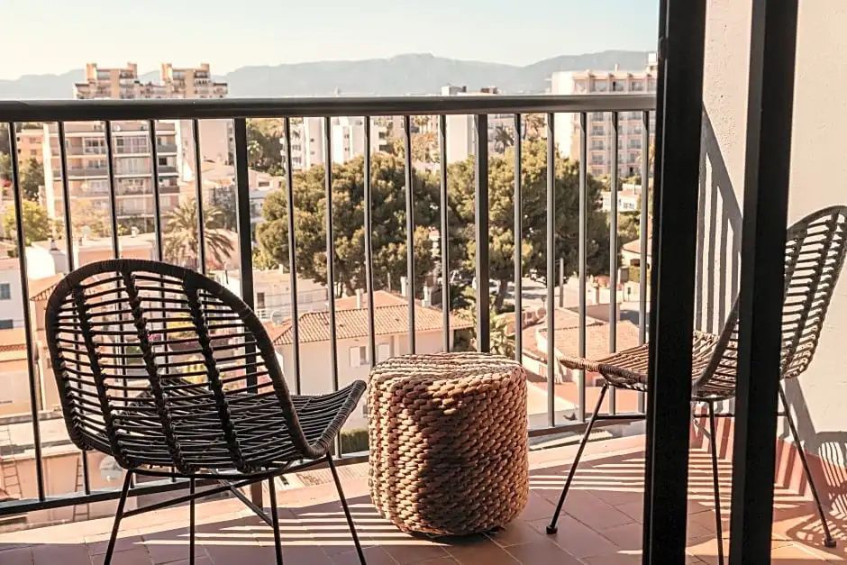 Balkon mit zwei Stühlen und Hocker sowie Ausblick über die Dächer der Stadt