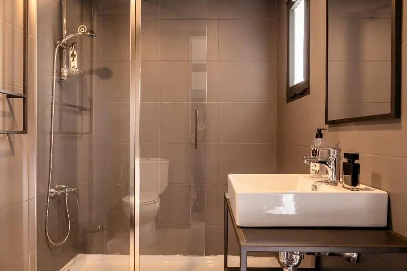Badezimmer mit weißem Waschbecken auf schwarzem Gestell und ebenerdiger Dusche