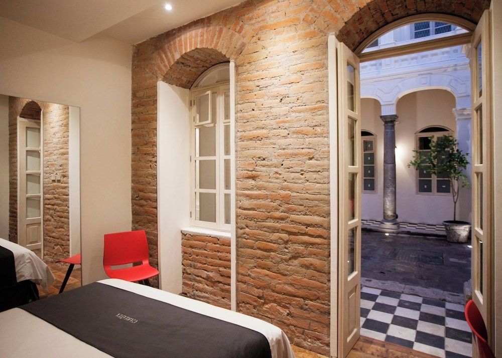 Hotelzimmer mit rustikaler Ziegelwand und geöffneter Tür zum Innenhof.