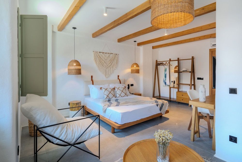 Hell gestaltetes Zimmer mit Holzbalkendecke, Doppelbett und Lampen aus Naturmaterialien.