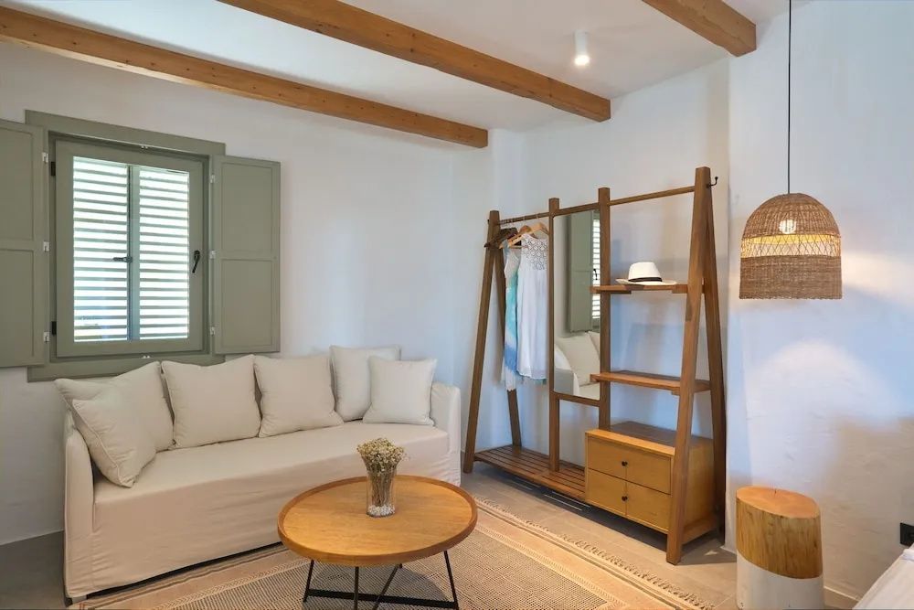 Sitzecke im Zimmer mit weißem Sofa, rundem Holztisch und offenem Kleiderständer.