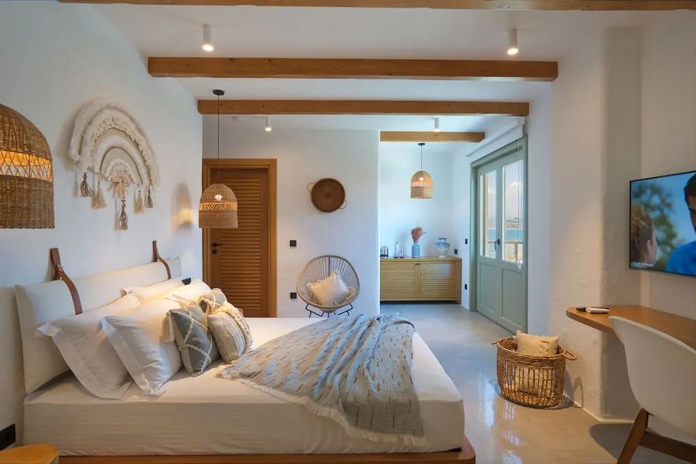 Blick durch das Schlafzimmer mit Doppelbett, Flechtlampen und Holzbalken an der Decke.