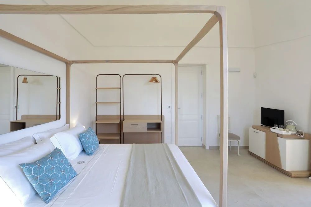 Helles Hotelzimmer mit modernem Himmelbett aus Holz und schlichten Möbeln.