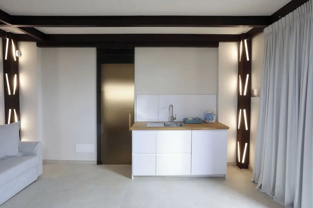 Kompakte weiße Küchenzeile mit Spülbecken und Arbeitsplatte aus Holz.