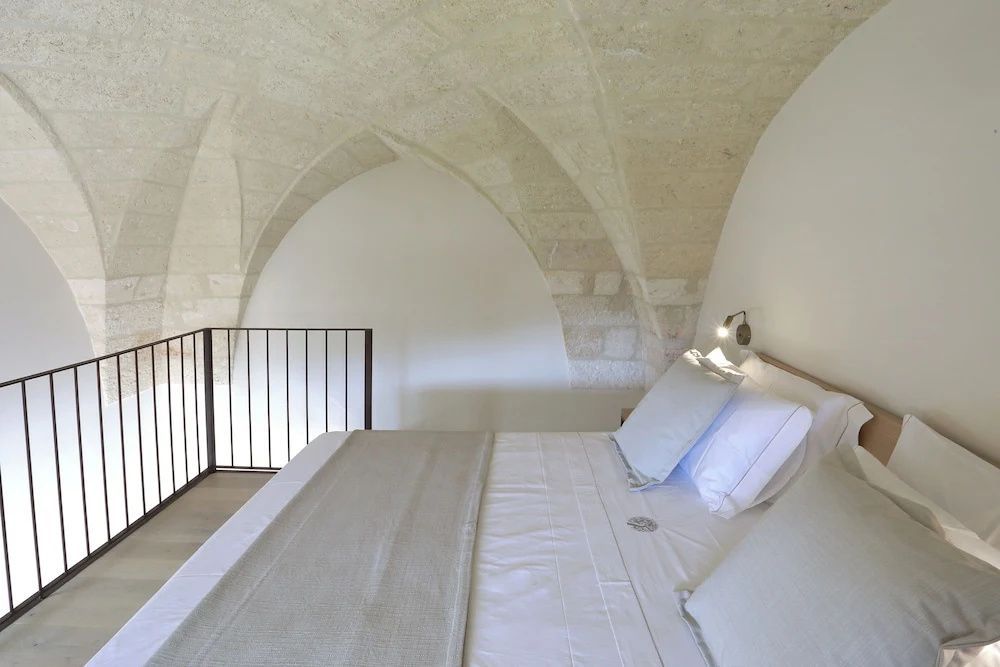 Doppelbett auf einer Empore unter einem historischen Steingewölbe.