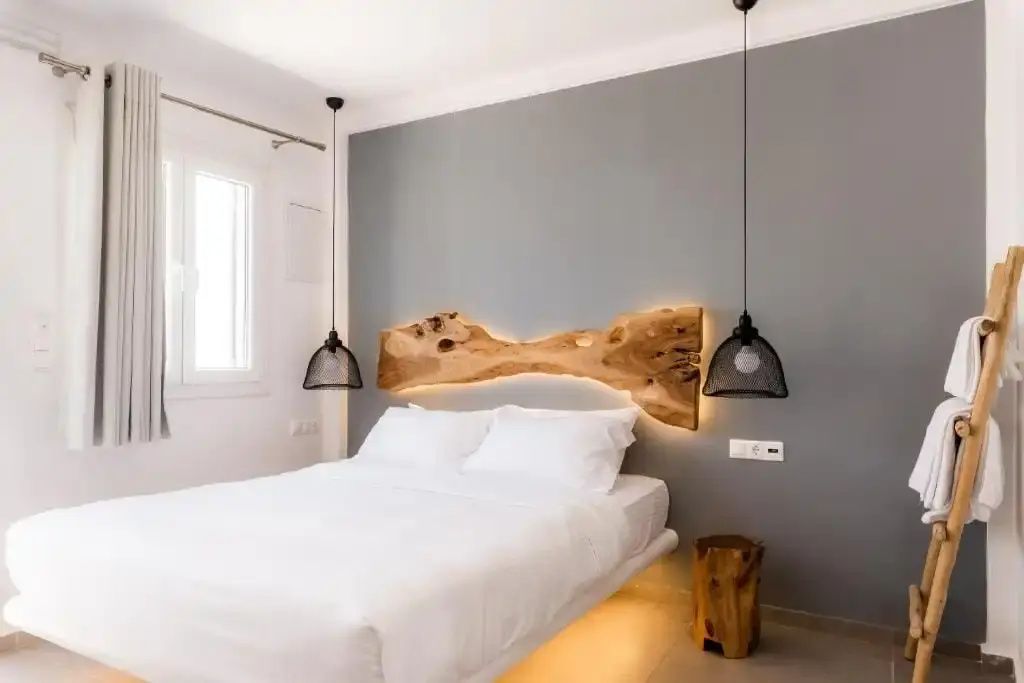 Doppelbett mit weißer Bettwäsche und einem beleuchteten Kopfteil aus Naturholz