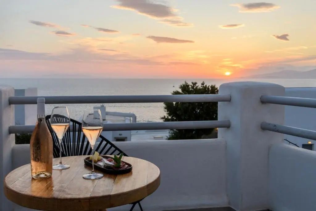 Blick von der Terrasse auf das Meer bei Sonnenuntergang mit Gläsern auf dem Tisch.