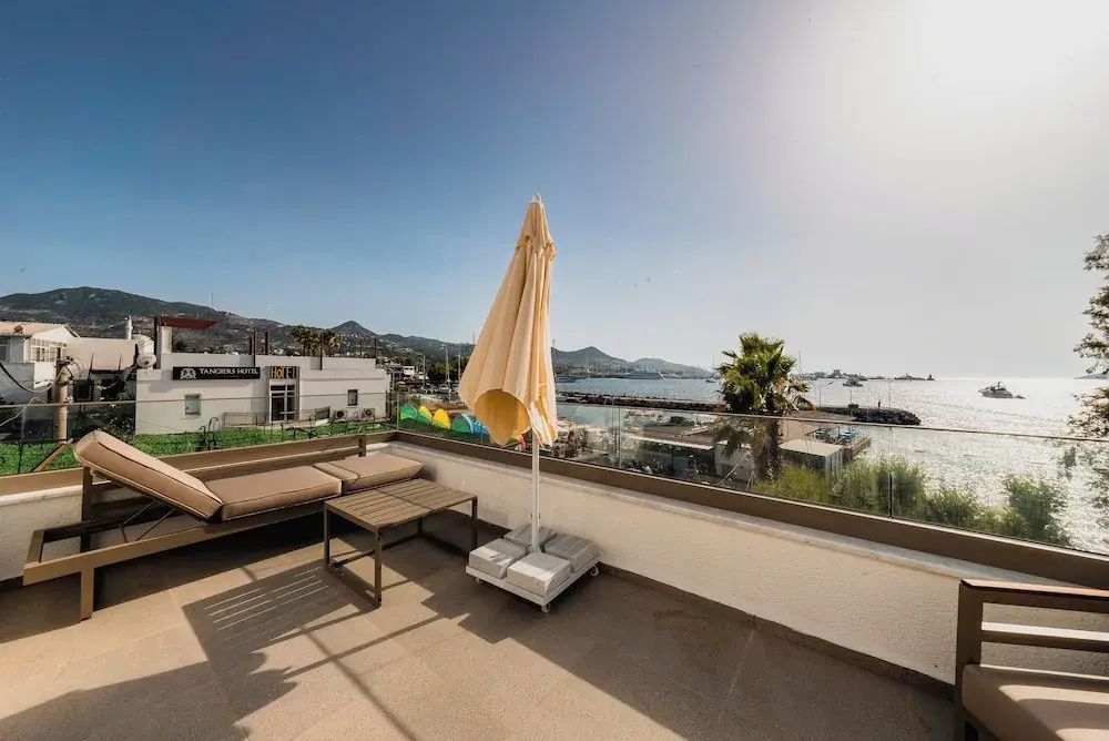 Dachterrasse mit Sofa, Couchtisch und Aussicht auf die Küste und Berge.