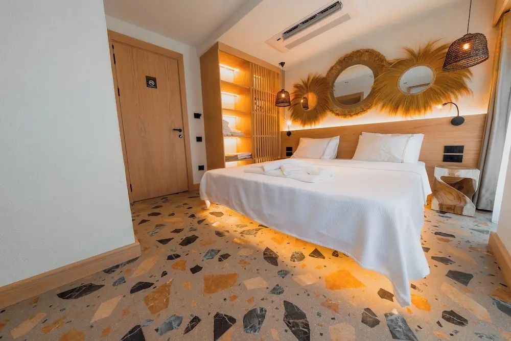 Blick in das Schlafzimmer mit Holztür, Terrazzoboden und Doppelbett.