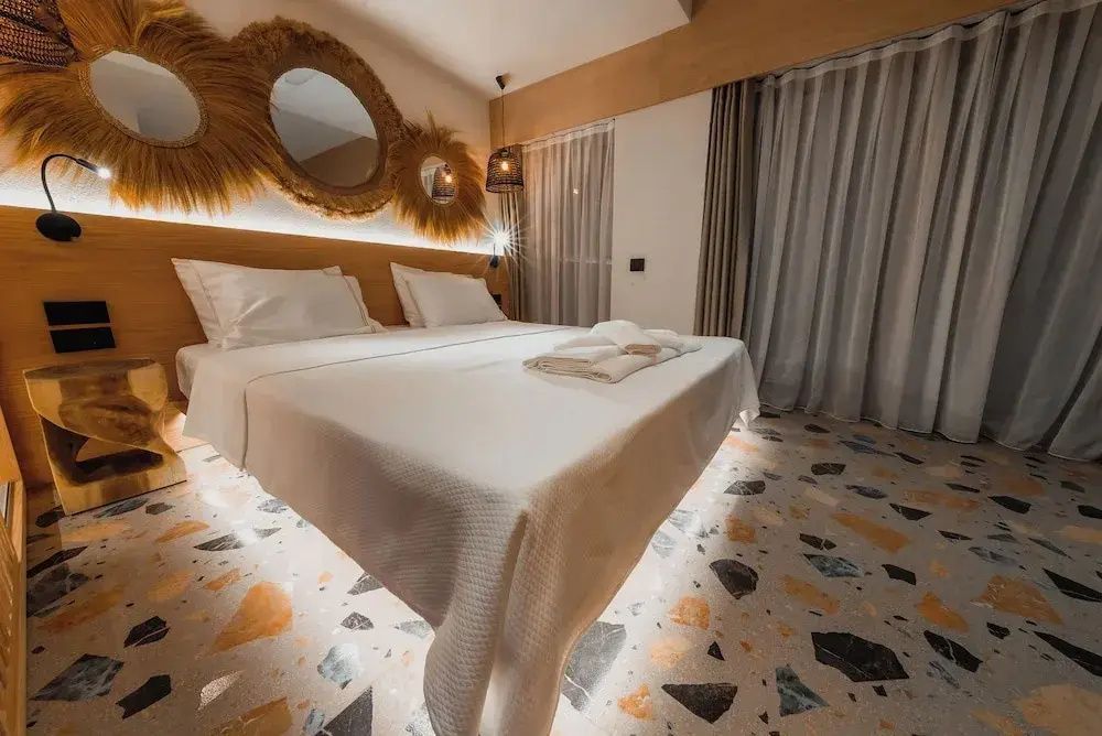 Doppelbett im Hotelzimmer mit indirekter Bodenbeleuchtung und Vorhängen.