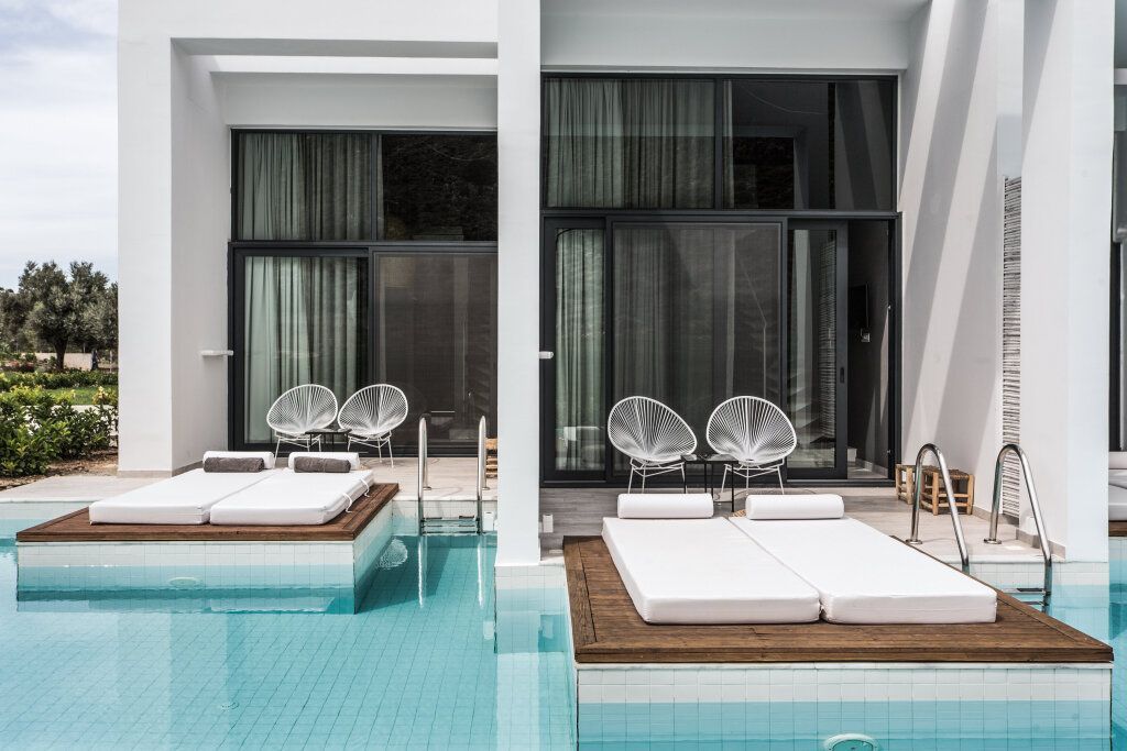 Zwei Swim-Up Zimmer mit Holzterrasse und Liegen direkt am geteilten Pool im Casa Cook Rhodos
