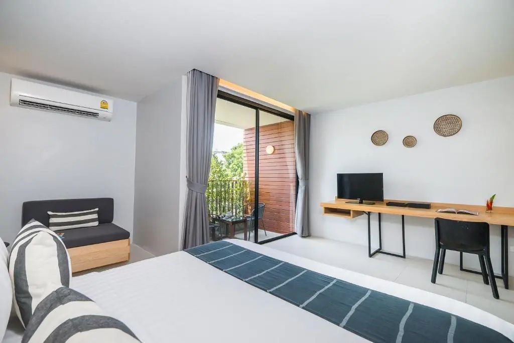 Zimmeransicht mit Bett im Vordergrund, TV-Wand und Balkonzugang.