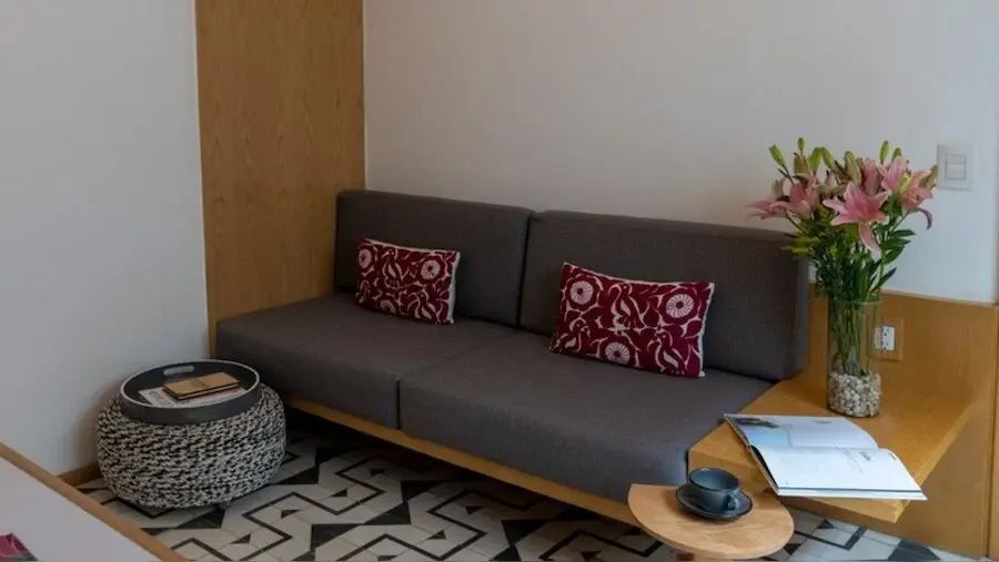 Graues Sofa mit zwei rot gemusterten Kissen auf einem Teppich mit Muster.